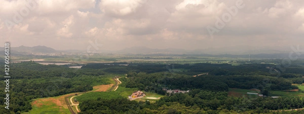 Fototapeta Aerial View Of North Korea, Green Forests, Rolling Hills, And Rural Landscape With Winding Roads Under Cloudy Sky