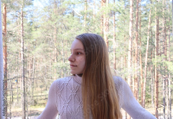 Obraz portrait of a young woman in a park. girl standing on a balcony. blond girl in a beige sweater looking aside