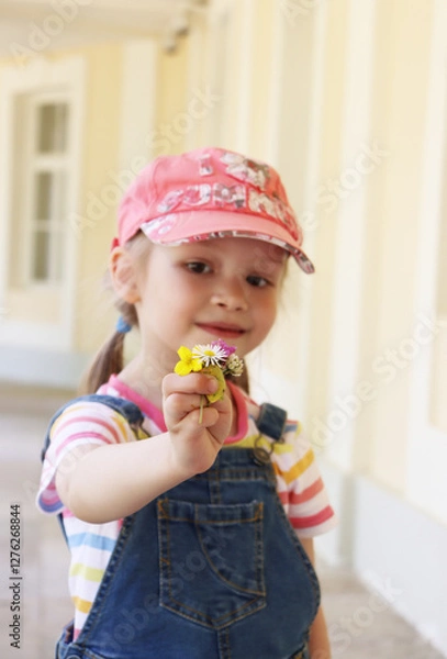 Fototapeta little girl showing a small bouquet of flowers to the camera. summer walk. flowers macro