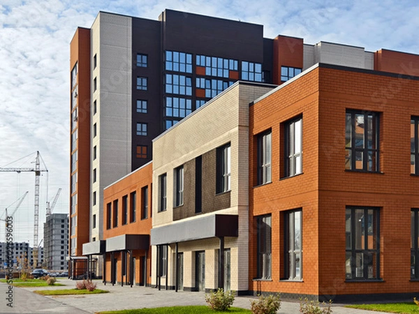 Fototapeta Side view on generic red brick office building with parking lot. Construction of a new residential area in the city. Development of the construction industry.