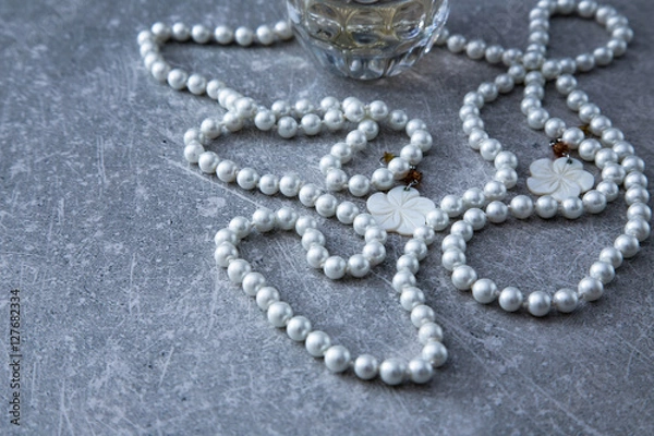 Obraz a strand of pearls and perfume on a stone background