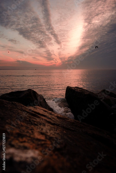 Obraz Sunrise over Buzzards Bay off the south coast of Massachusetts. This photo was taken from Gooseberry Island. It shows a wave crashing over ocean rocks while gulls fly in front of the rising sun.