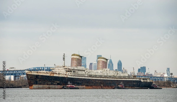 Fototapeta The SS United States Liner on it's way to Destin Florida where it will become an artificial reef sales past the Philadelphia Skyline where it's been docked since 1996
