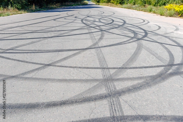 Obraz Skid marks on the road surface. Circular tire tracks left by drivers making donuts. Tire print on asphalt road