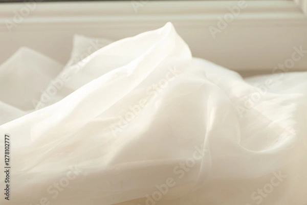 Obraz Elegant, soft, and flowing fabric is draped in a relaxed way, letting the light shine through its delicate texture by a window.