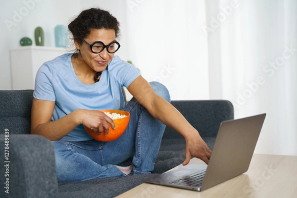 Obraz Happy black woman is watching a streaming movie at home