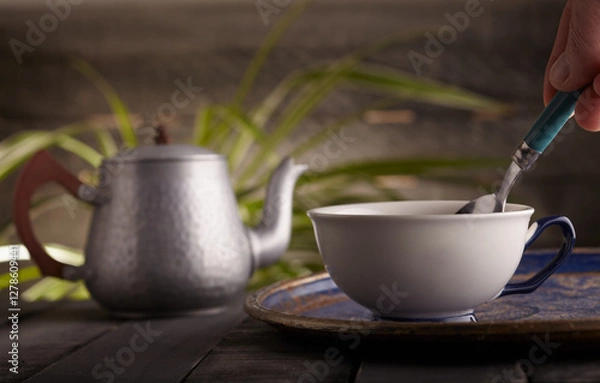 Obraz Cup of tea with a tea pot in the background.