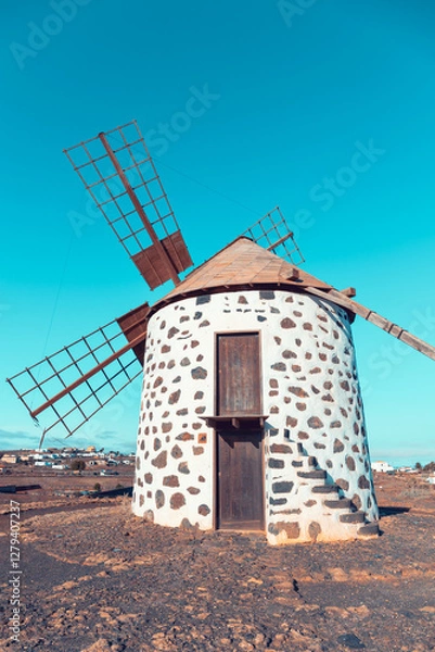 Fototapeta View of the old, typical windmills of Villaverde, Fuerteventura, Canary Islands, with their wooden blades. almost sunset, oblique light, golden hour. Past, vintage feeling.