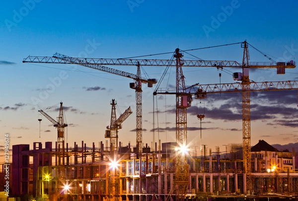Obraz Silhouettes of tower cranes against the evening sky. House under construction. Industrial skyline