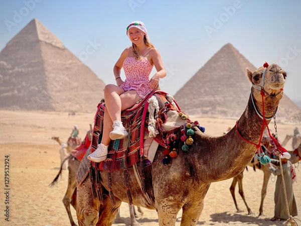 Fototapeta Smiling woman on a camel with the pyramids of Giza in the background.