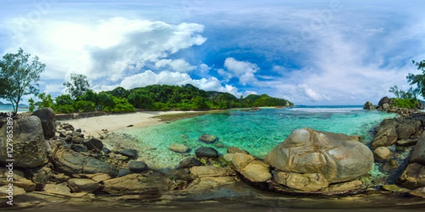Fototapeta Crystal-clear waters surround smooth rocks on a small beach, with a backdrop of greenery under a bright sky. Port Glaud Lagoon. Seychelles. VR 360.