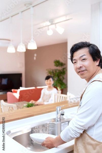 Fototapeta 皿洗をする男性と寛ぐ女性