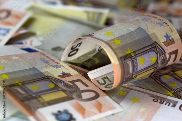 Obraz Half rolled fifty euro banknote on fifty euros banknotes background. Close up shot, Selective focus.