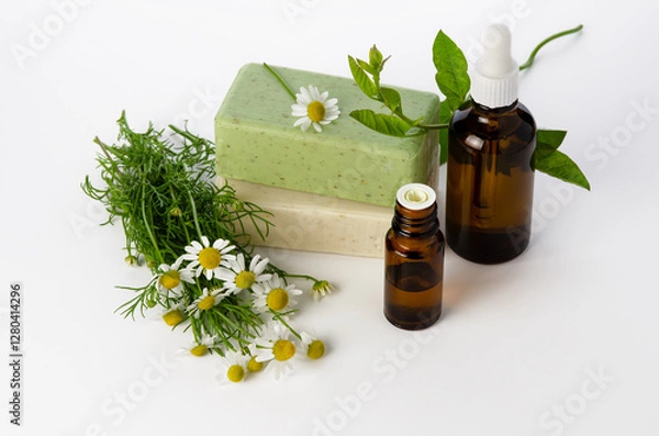 Obraz Chamomile oil in glass bottle and soap bars with flowers on white background