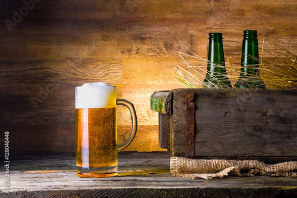 Fototapeta mug of beer with the old box of beer and bottles on wooden background