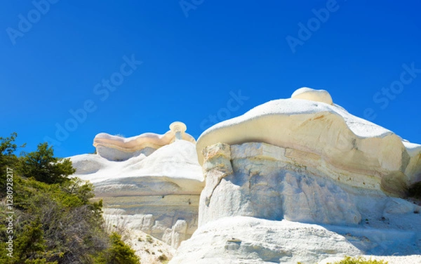Fototapeta Amazing limestone eroded rock formations with layered textures shaped by natural forces. Green vegetation contrasts with pale stone, highlighting geological beauty of Cappadocia