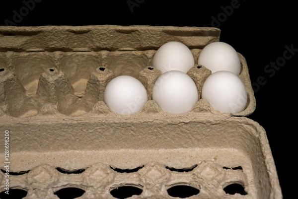 Fototapeta Five remaining unused white chicken eggs in an open carton box on a dark background