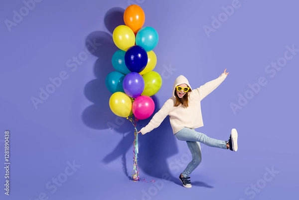 Fototapeta Young girl in casual pullover posing cheerfully with multicolored balloons against purple background