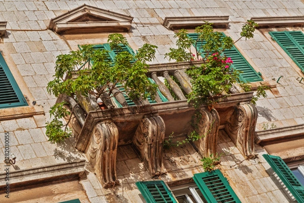 Fototapeta Old windows and balconies in old stone wall with plants