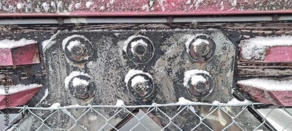 Fototapeta Metal bolts on foot bridge in winter with cold rime closeup