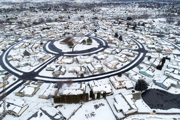 Fototapeta A snowy town with houses and a round street