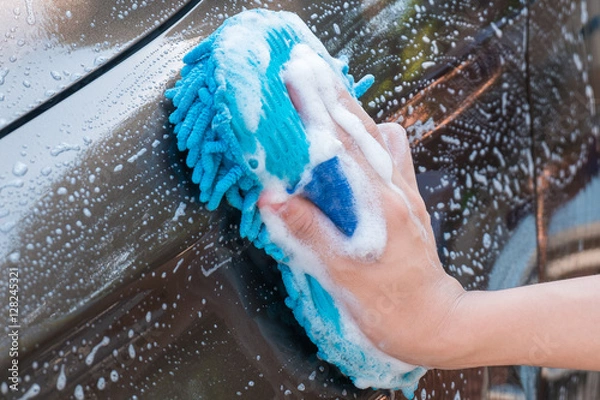 Fototapeta Close up of Male Hand Washing Brown Car with Blue Sponge and Bubbles (Foam)