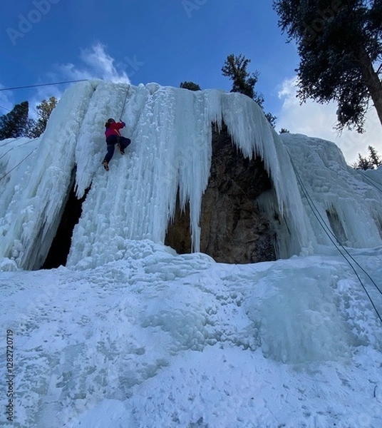 Fototapeta Climber scaling a frozen waterfall