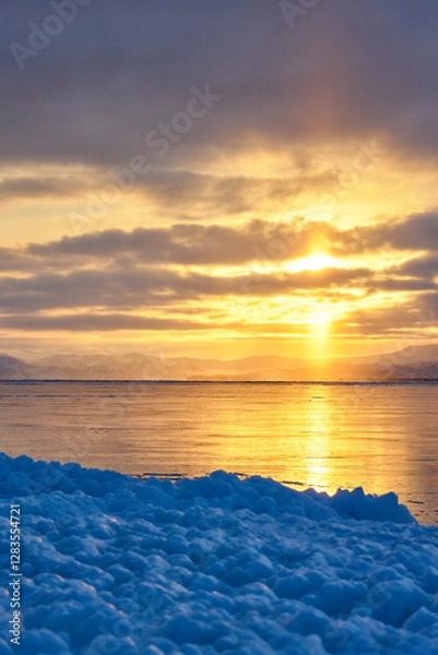 Fototapeta A beach covered with uneven ice against the background of a sunset on Lake Baikal in winter