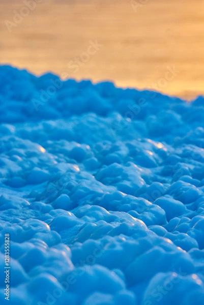 Fototapeta Uneven blue ice against a red sunset background