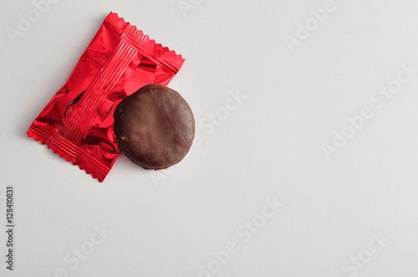 Obraz A round biscuits covered in chocolate with a red wrapper