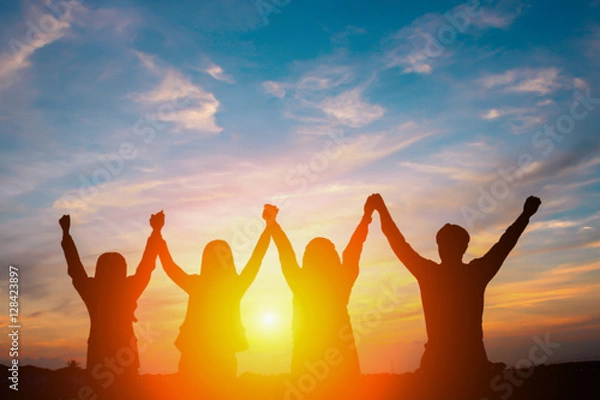 Fototapeta Silhouette of happy business team making high hands in sunset sky