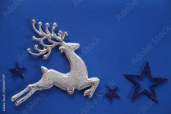 Fototapeta Beautiful Christmas silver deer close up isolated on a blue background. Adorable reindeer with presents for christmas decoration.
