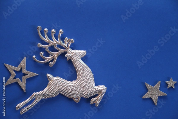 Fototapeta Beautiful Christmas silver deer close up isolated on a blue background. Adorable reindeer with presents for christmas decoration.
