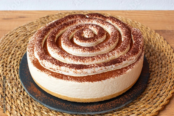 Fototapeta Coffee cheesecake on a black slate plate, wooden table, and white background