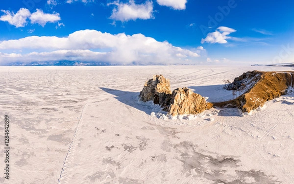 Fototapeta Aerial top view to famous Shamanka rock and small sea covered with snow. Winter landscape. Popular touristic destination, Clear ice. Cape Burkhan on Olkhon island, frozen Baikal lake, Siberia, Russia.