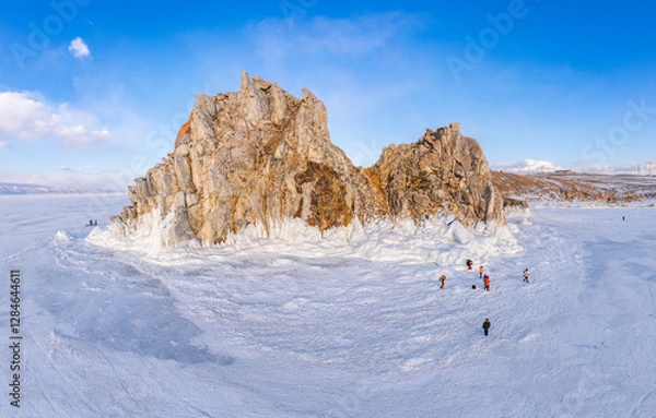 Fototapeta Aerial top view to famous Shamanka rock and small sea covered with snow. Winter landscape. Popular touristic destination, Clear ice. Cape Burkhan on Olkhon island, frozen Baikal lake, Siberia, Russia.