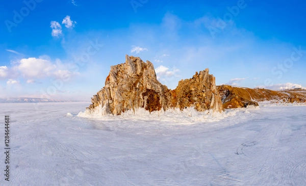 Fototapeta Aerial top view to famous Shamanka rock and small sea covered with snow. Winter landscape. Popular touristic destination, Clear ice. Cape Burkhan on Olkhon island, frozen Baikal lake, Siberia, Russia.