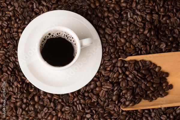 Obraz coffee cup on a bed of beans and a serving spoon  shot from abov