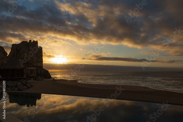 Fototapeta The sun and its rays breaking through at dawn over the Sea of Cortez and reflecting in the pool by the beach.