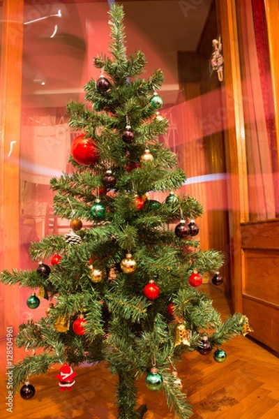 Fototapeta Artificial Christmas tree with colorful ornaments on red background