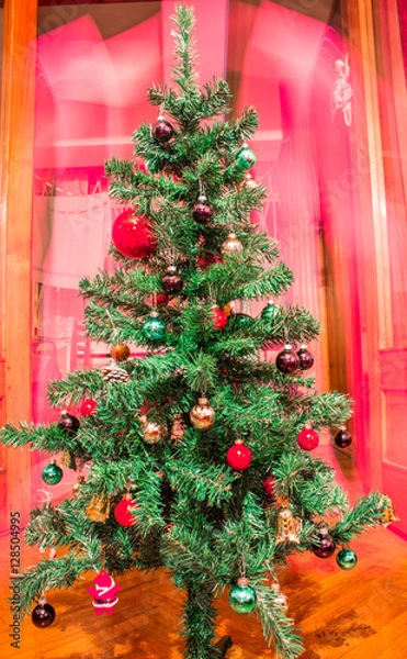 Fototapeta Artificial Christmas tree with colorful ornaments on red background 