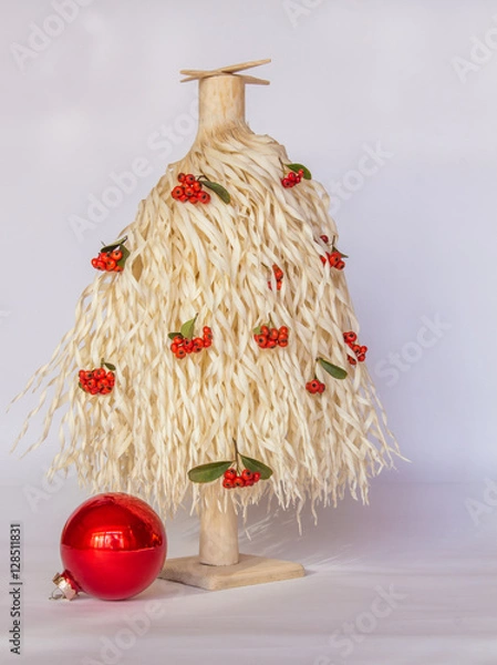 Fototapeta White wood shavings Christmas tree with red berries and one big red ornament