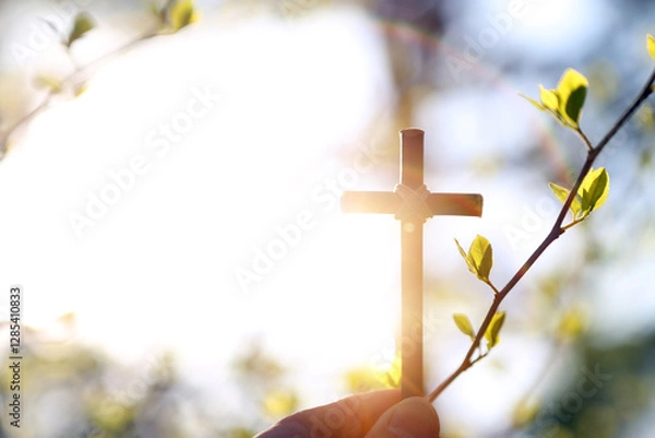 Obraz Bright spring background with warm sunshine and new life sprouting, holy cross of Jesus Christ and green buds
