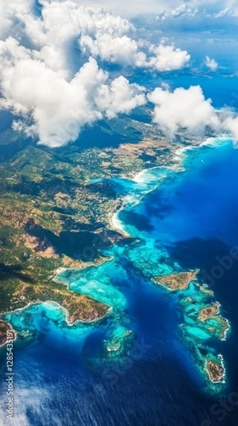 Fototapeta Aerial View of a Tropical Coastline Featuring Vibrant Blue Waters and Lush Green Hills Under a Partly Cloudy Sky