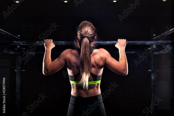 Fototapeta Strong girl in sportswear doing pull up exercise
