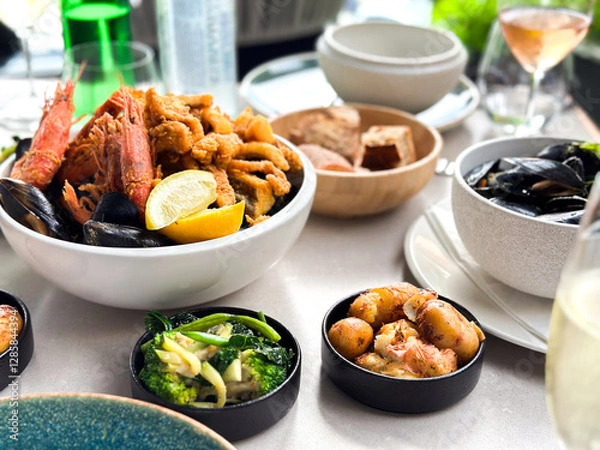 Fototapeta Seafood in a bowl with shrimps, shells, lemon and fried octopus with vegetables, potatoes and bread