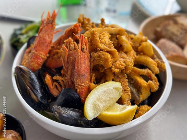 Fototapeta Seafood in a bowl with shrimps, shells, lemon and fried octopus with vegetables, potatoes and bread
