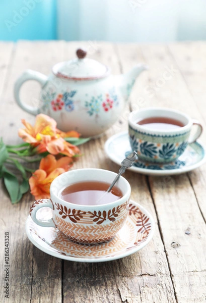 Obraz A beautiful ceramic cups and saucers with tea on a old wooden table with tea pot. Selective focus.
