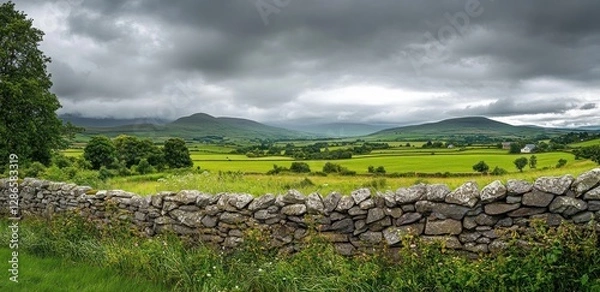 Fototapeta Serene Irish Countryside: Stone Wall and Rolling Hills Under a Cloudy Sky
