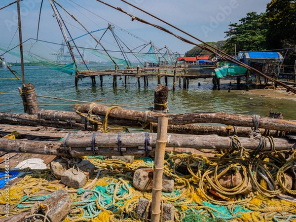 Fototapeta Chinese-style fishing nets, made from teak and bamboo, counterweighted by rocks, on the shoreline of Fort Kochi, a district of Kochi city in Kerala, southern India.